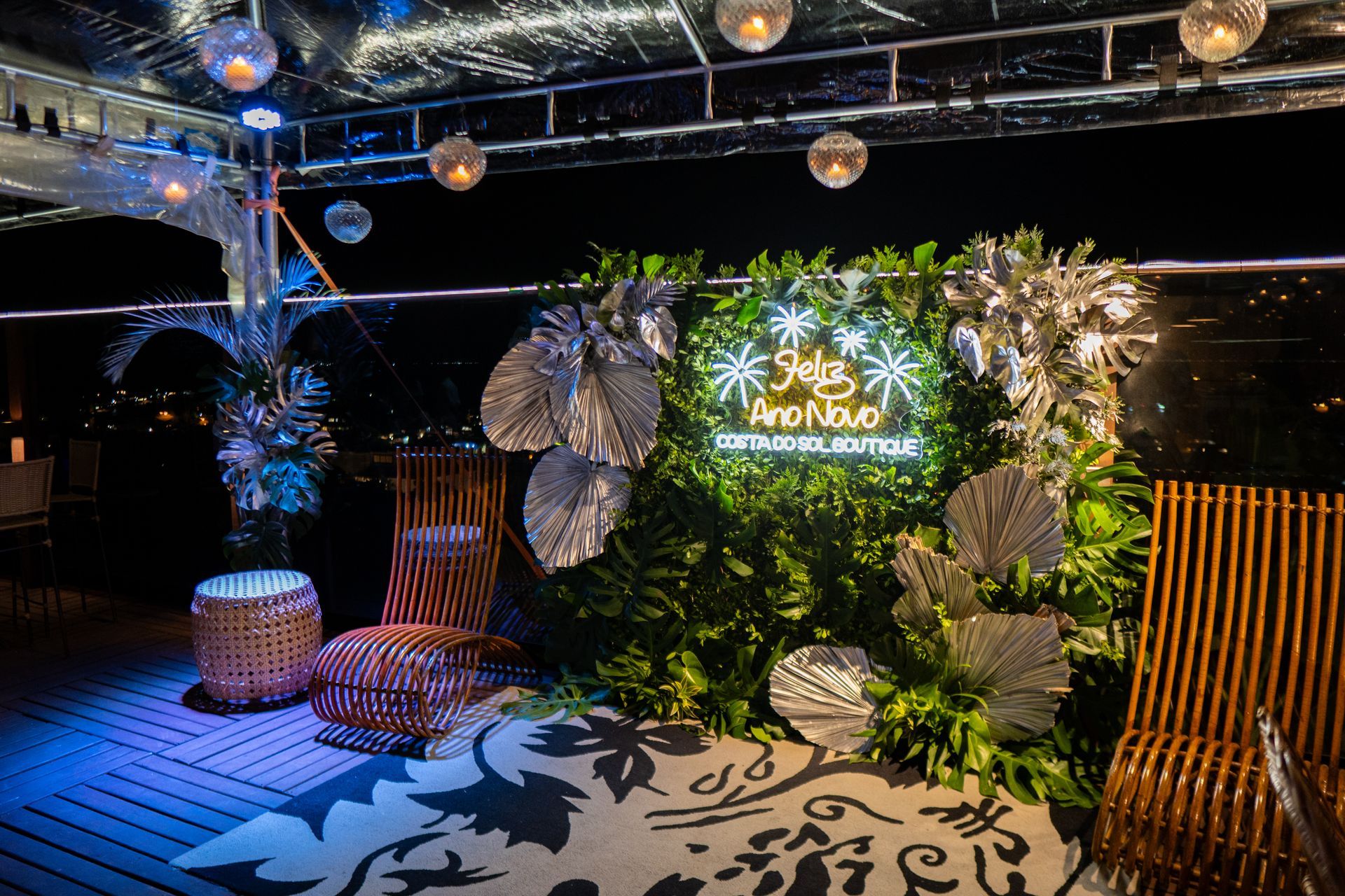 Vista aérea de uma área de piscina com guarda-sóis azuis, espreguiçadeiras e um gazebo em um dia ensolarado.