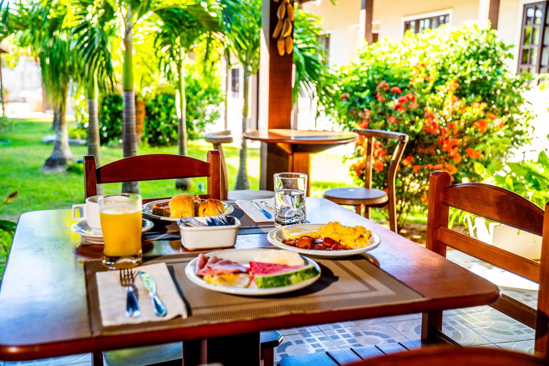 Uma mesa com pratos de comida e um copo de suco de laranja sobre ela.