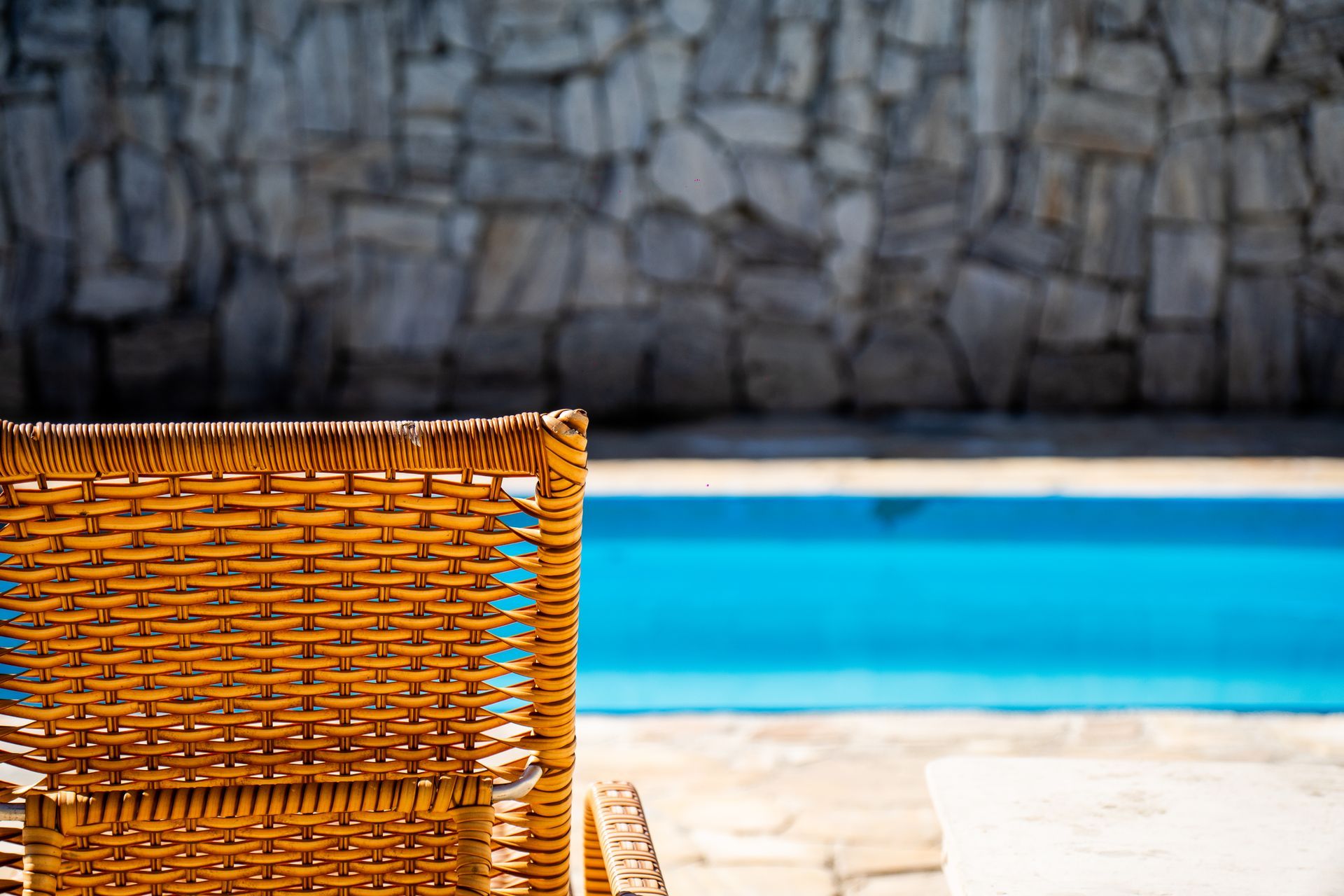 Uma cadeira de vime está ao lado de uma piscina.