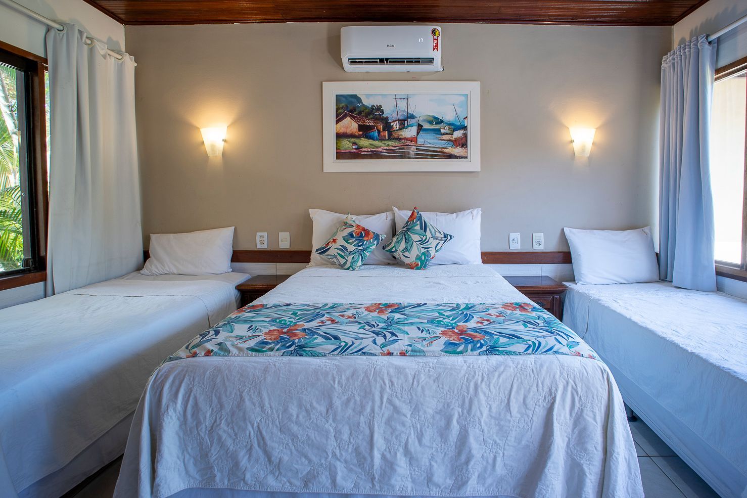 Um quarto de hotel com três camas e uma cama grande.