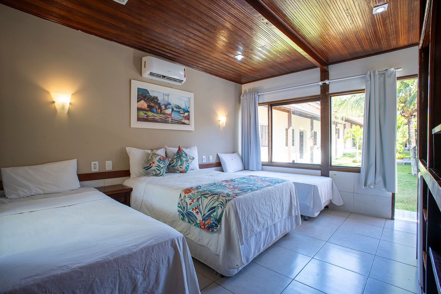 Um quarto de hotel com três camas e uma grande janela.