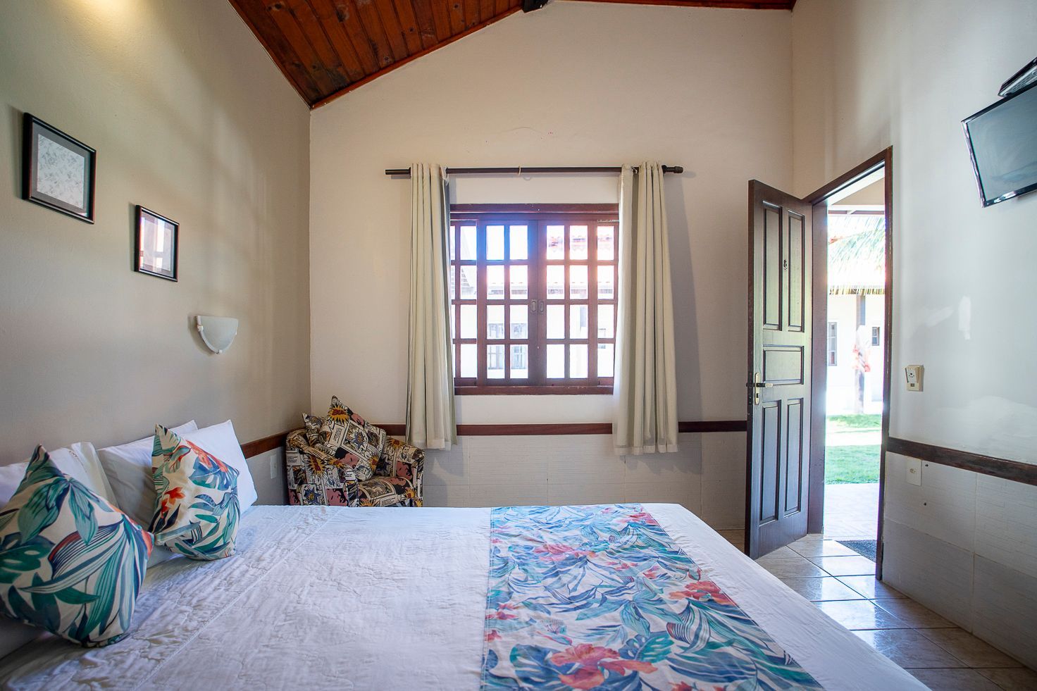 Um quarto com uma cama, cadeira, janela e porta.
