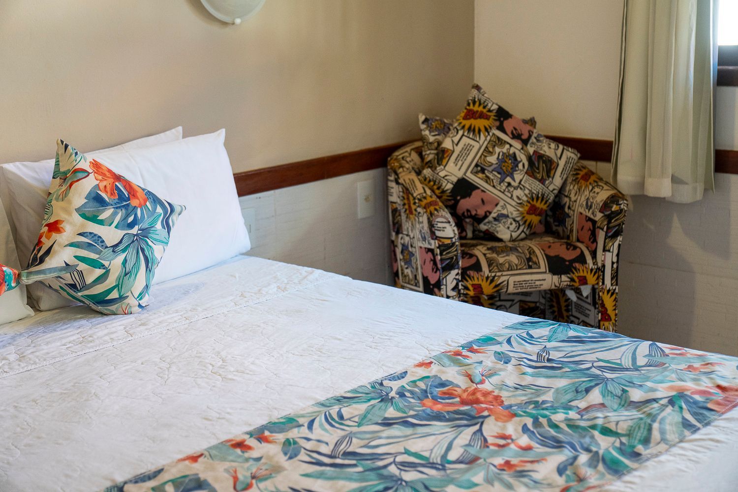 Há uma cama e uma cadeira no canto do quarto.