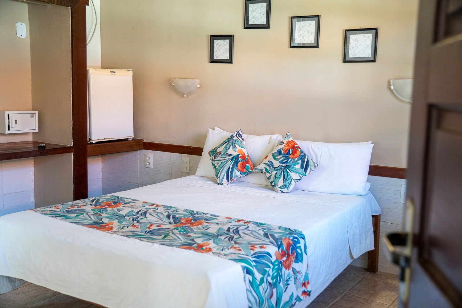 Um quarto de hotel com uma cama e uma geladeira.