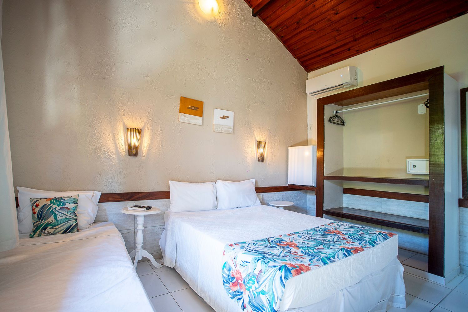 Um quarto de hotel com duas camas e um armário.