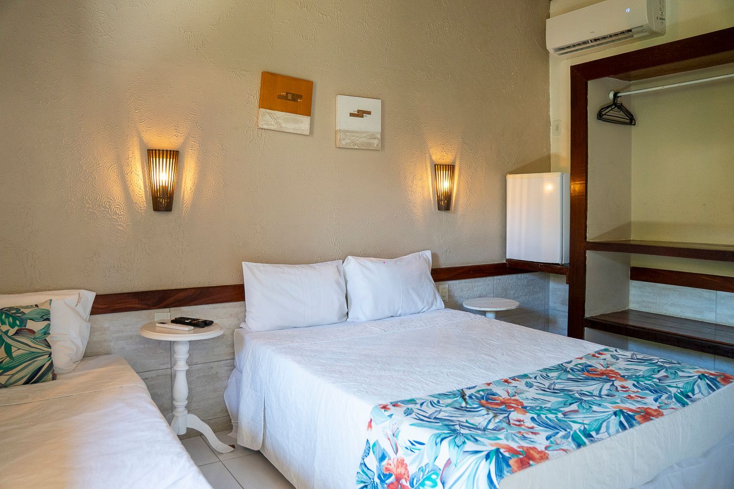 Um quarto de hotel com uma cama king size e duas camas de solteiro.