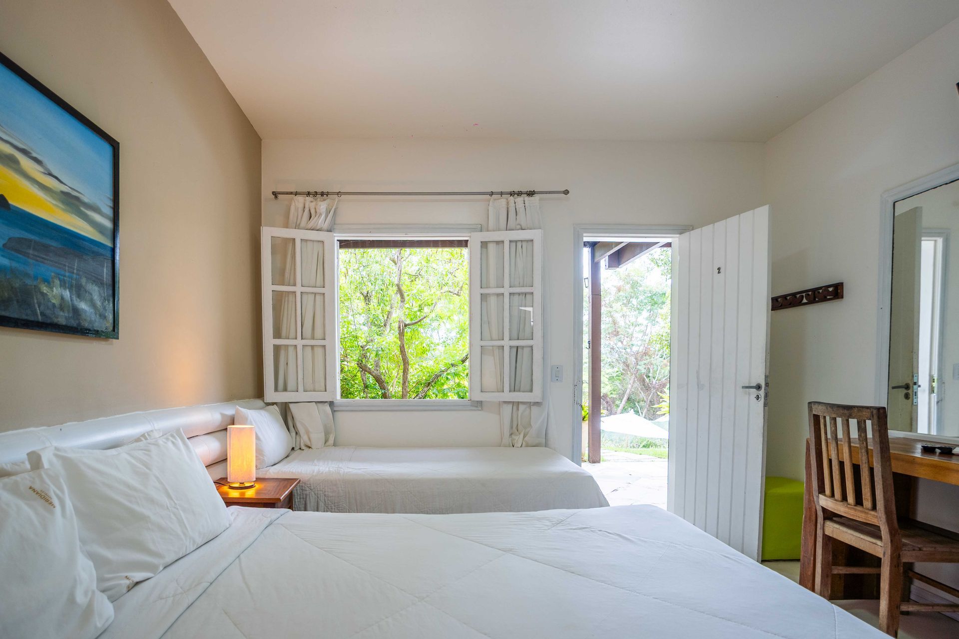 Um quarto de hotel com duas camas, uma escrivaninha e uma janela.