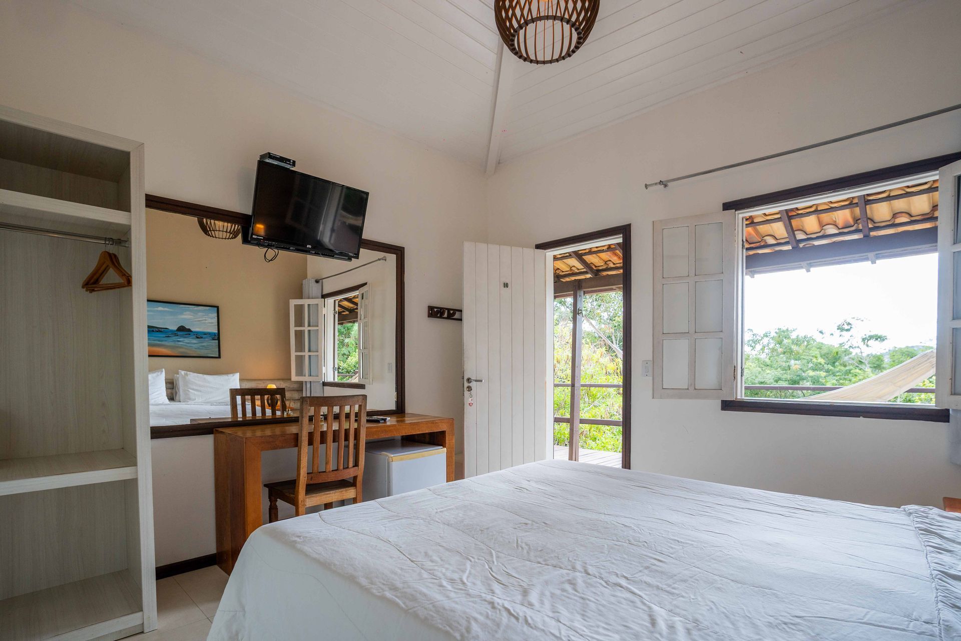 Um quarto de hotel com uma cama, escrivaninha, cadeira e televisão.
