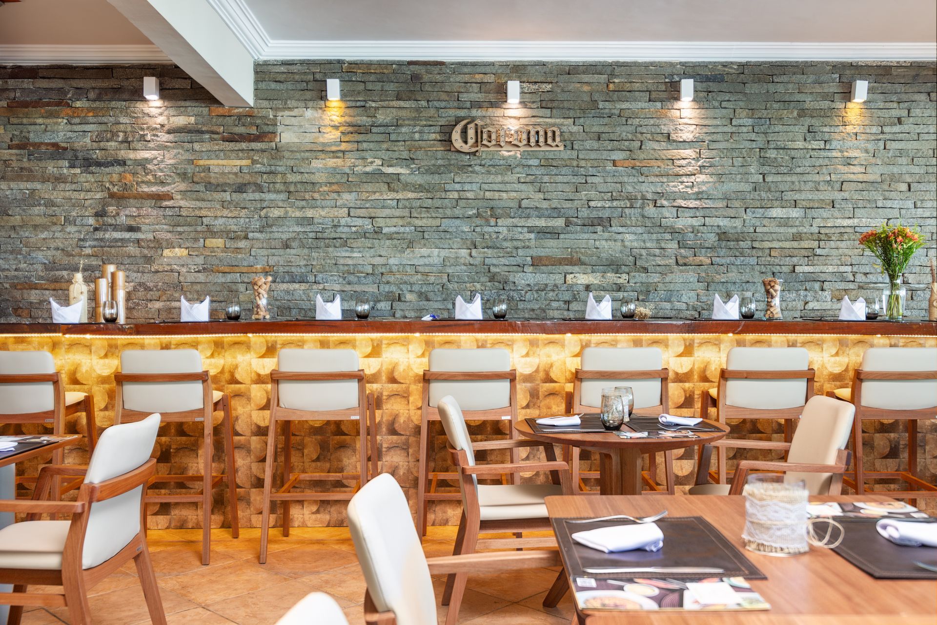 Um restaurante com mesas e cadeiras e uma parede de tijolos atrás do bar.