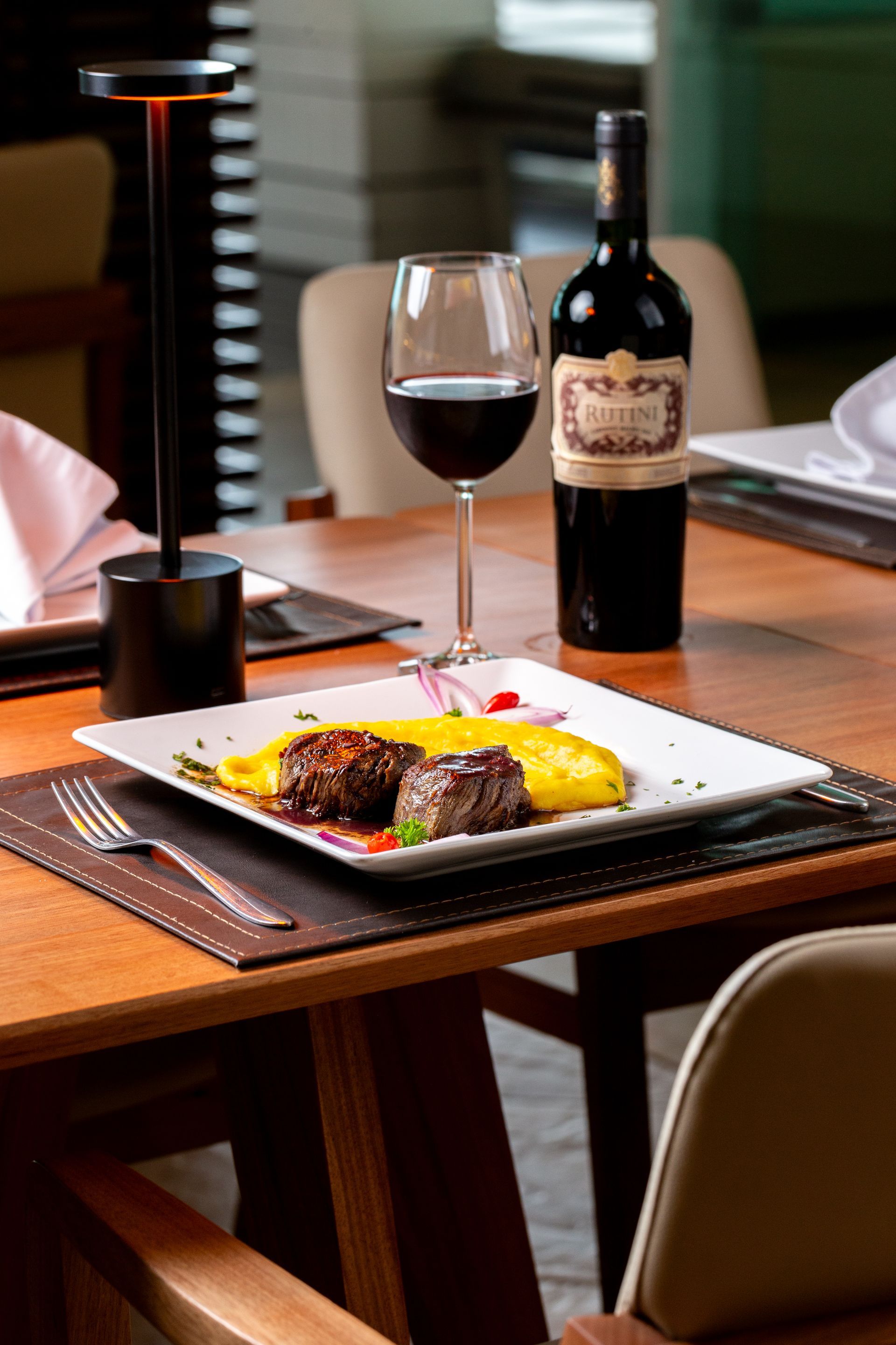 Uma garrafa de vinho e uma taça de vinho estão sobre uma mesa com um prato de comida.