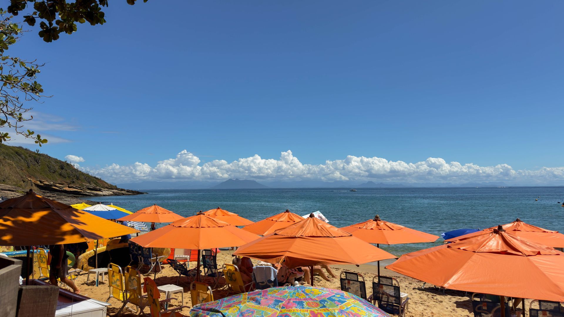 Uma praia com muitos guarda-sóis e cadeiras laranja