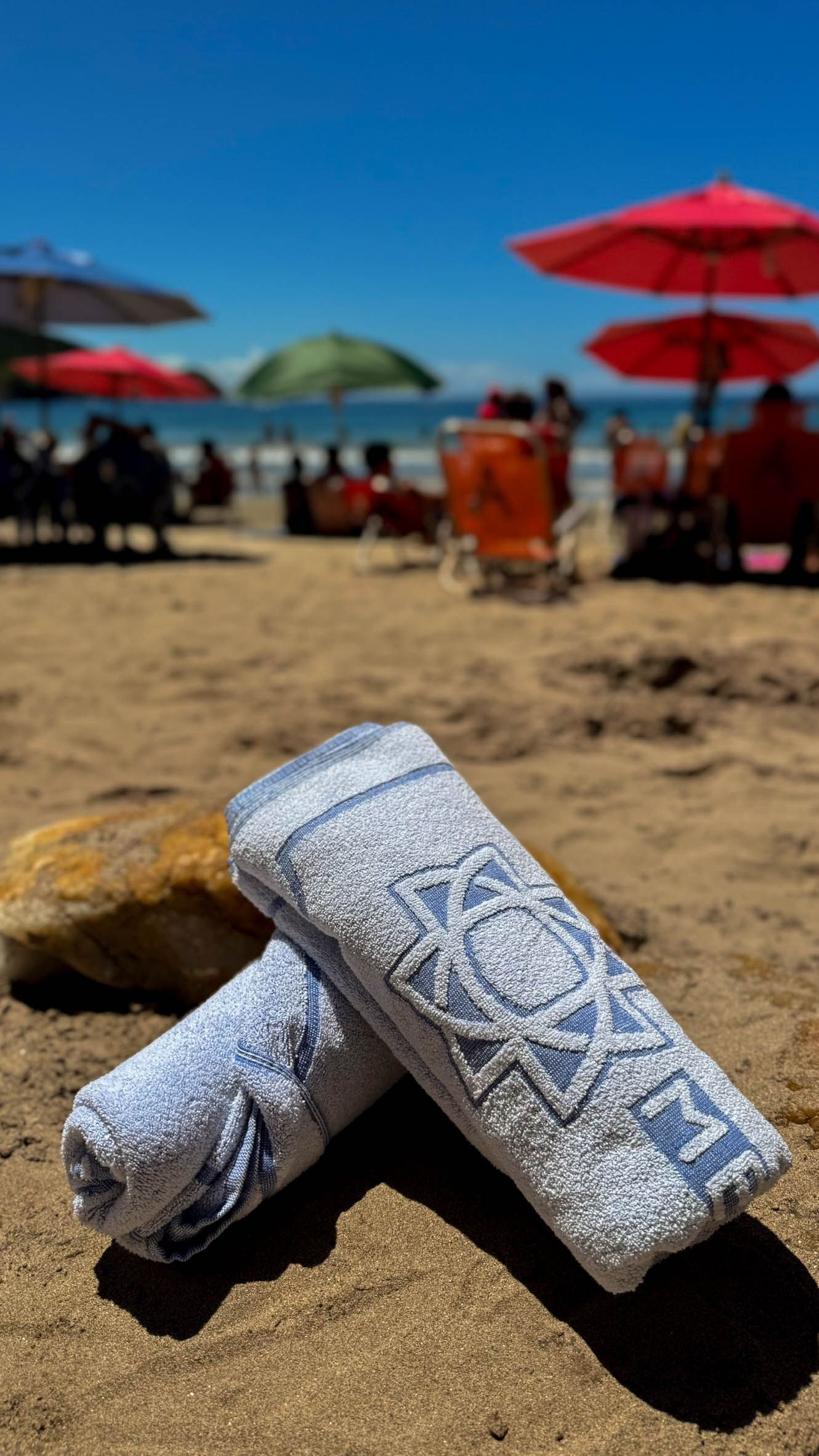 Duas toalhas estão empilhadas uma sobre a outra na praia.