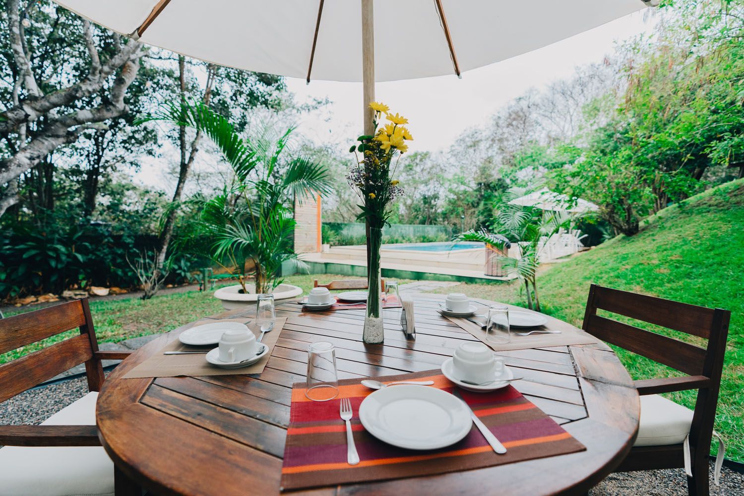 Uma mesa com pratos e xícaras sob um guarda-chuva