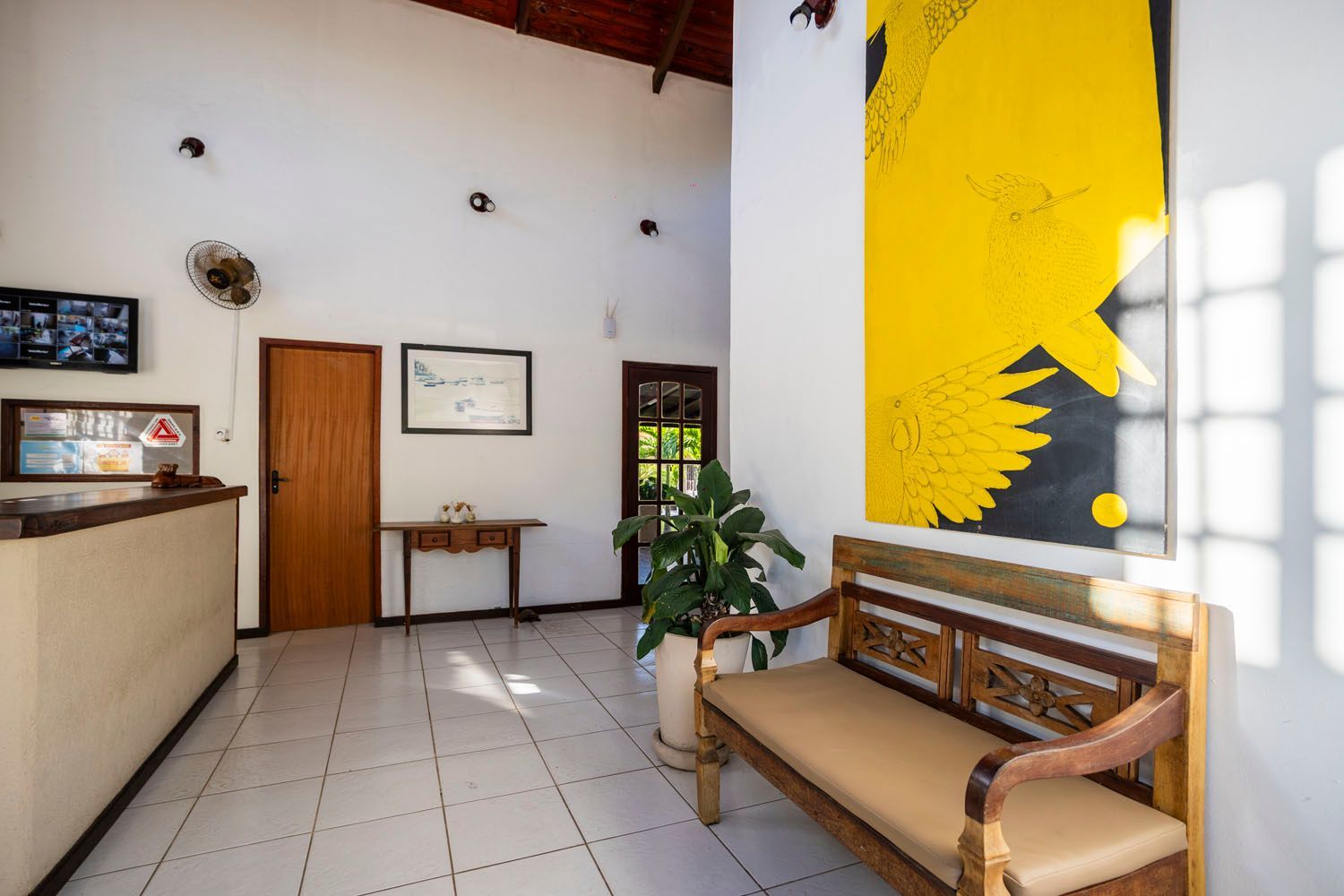 Uma sala de espera com um banco e uma pintura de um girassol na parede.