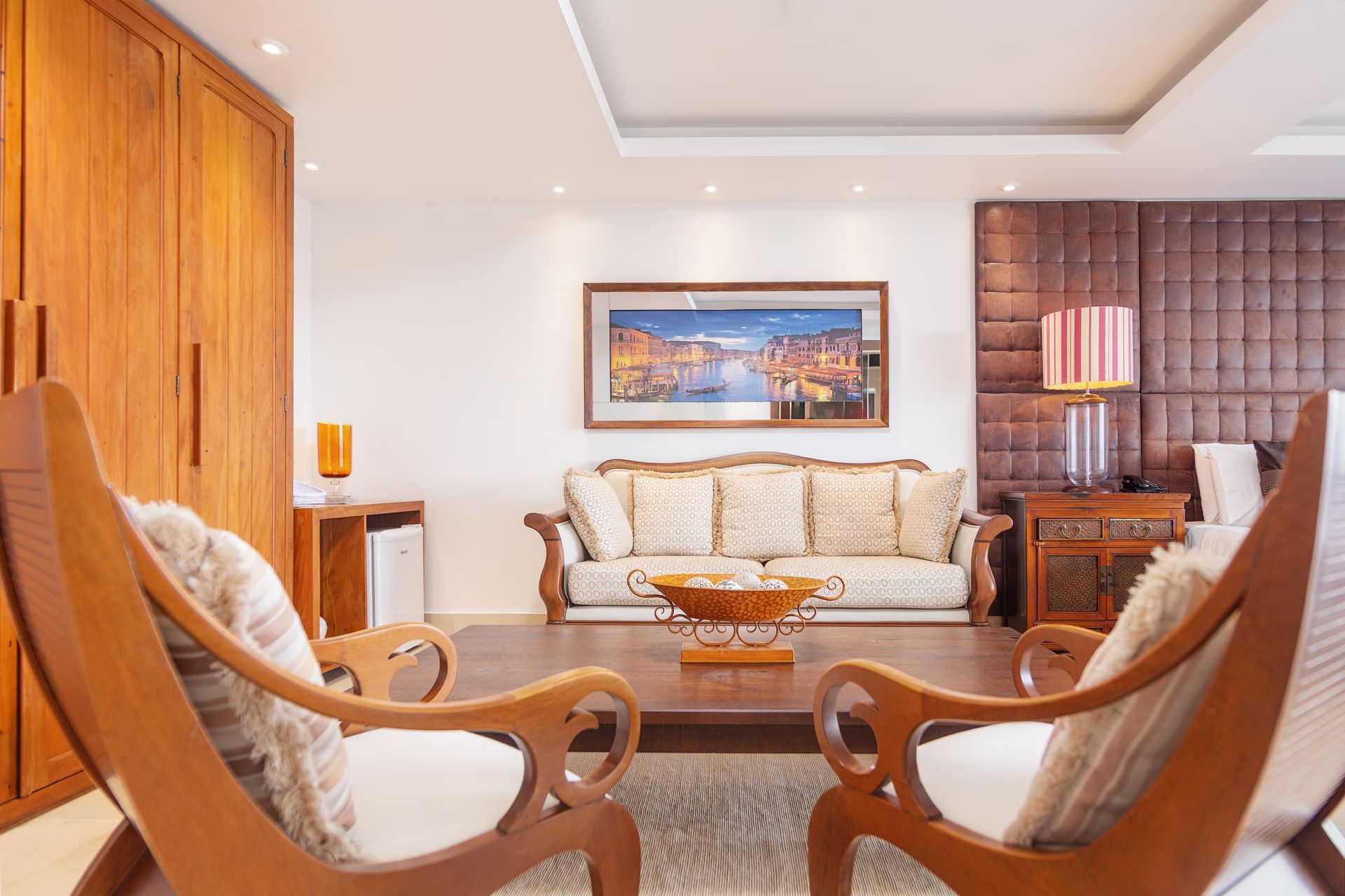 Uma sala de estar com um sofá e cadeiras e um quadro na parede