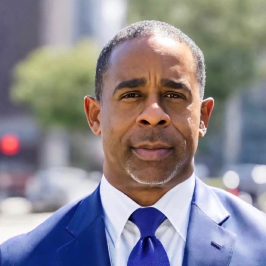 A man in a suit and tie looks at the camera