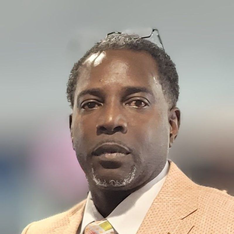 A man wearing a suit and tie is looking at the camera.