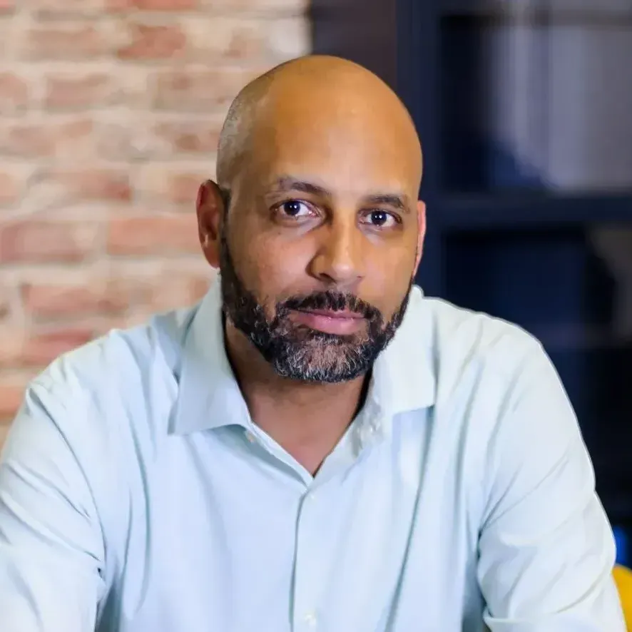 A bald man with a beard is sitting in a yellow chair