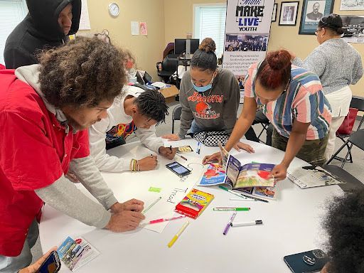A group of people are sitting around a table writing on a piece of paper.
