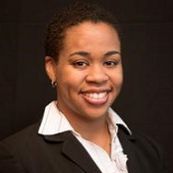 A woman in a suit and white shirt is smiling for the camera.