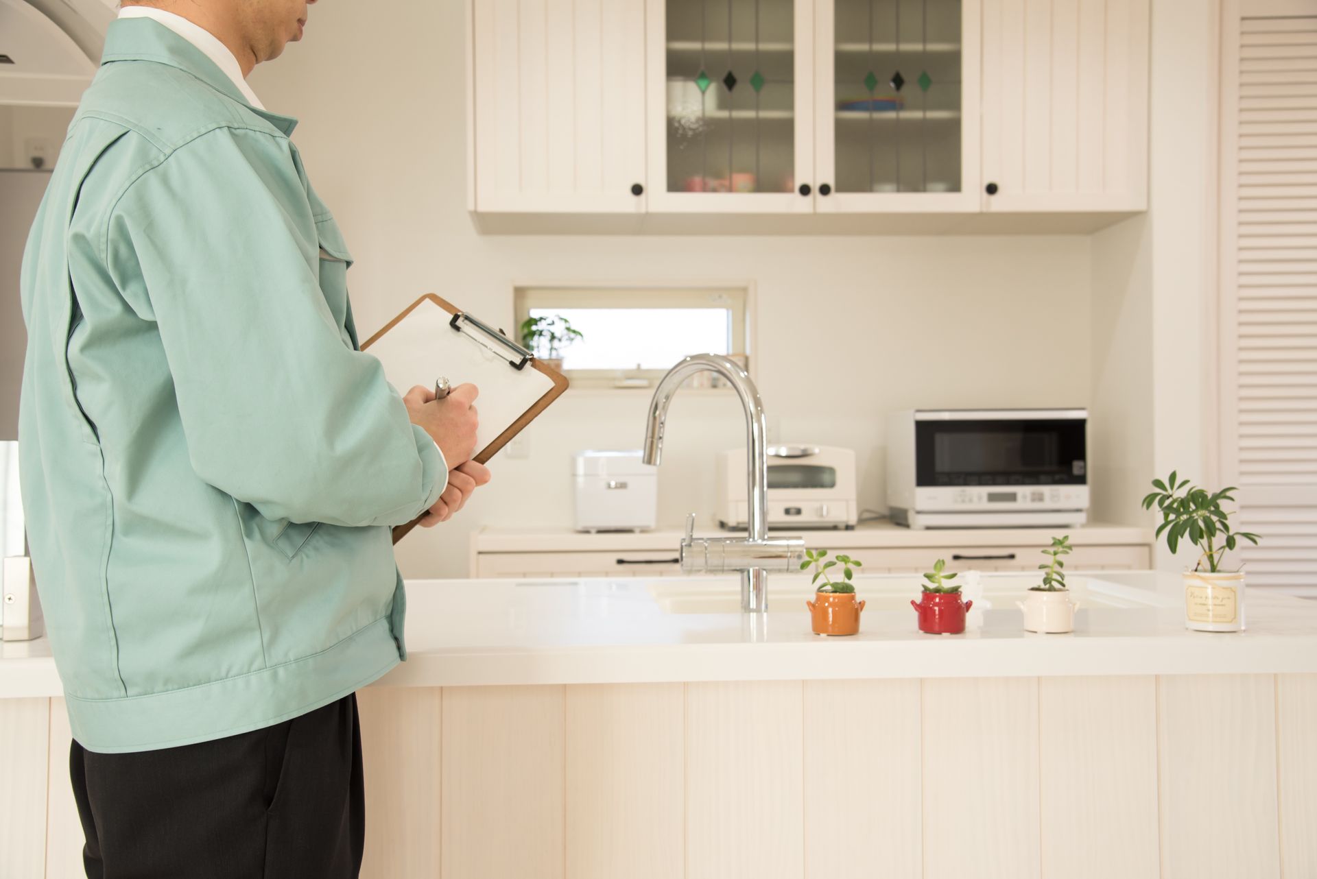 Un homme se tient debout dans une cuisine et tient un presse-papiers.