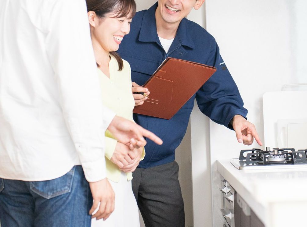 Un homme tient un presse-papiers et pointe du doigt un poêle tandis qu'une femme regarde.