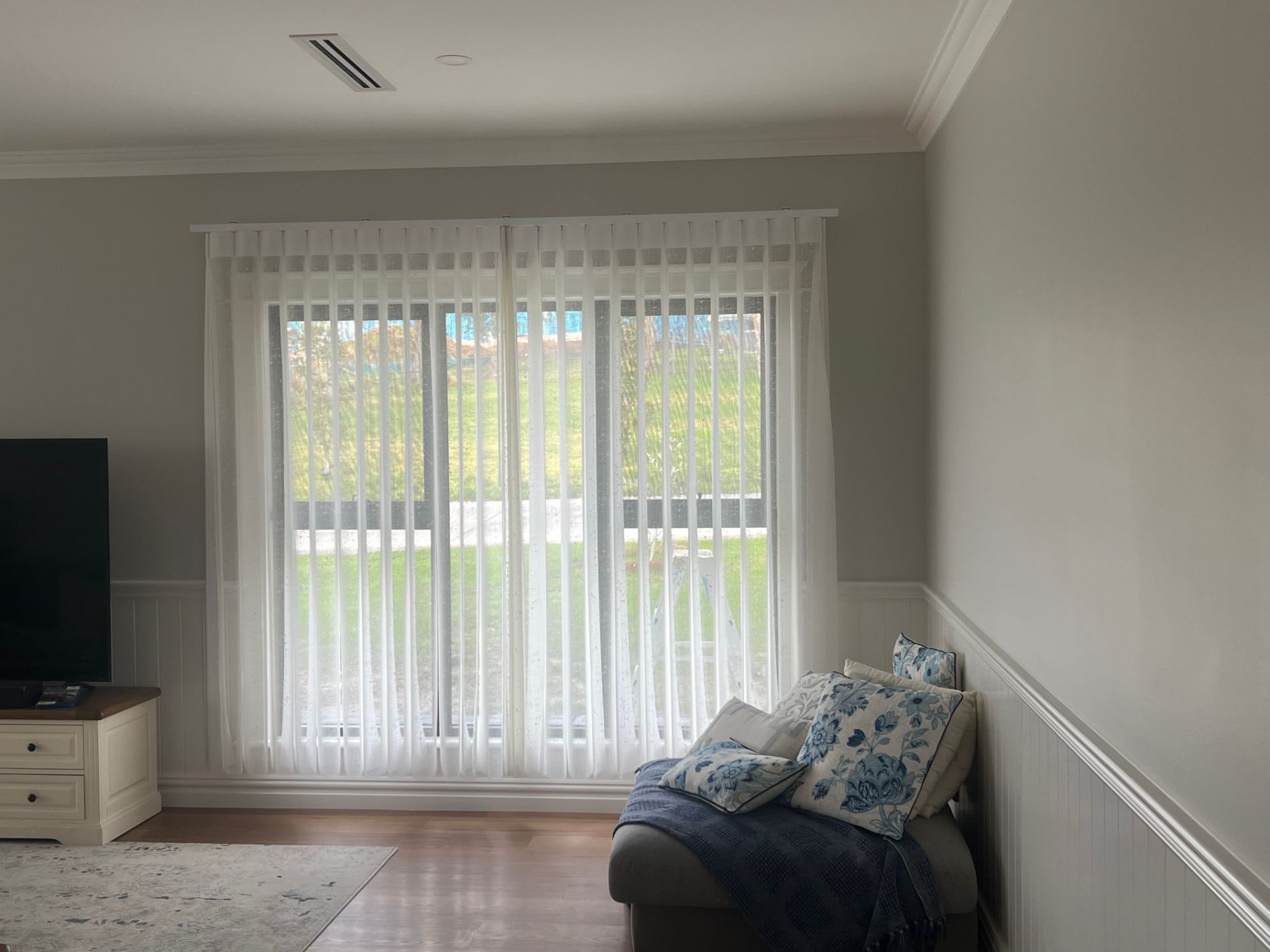 A living room with a couch , television , and sliding glass doors.