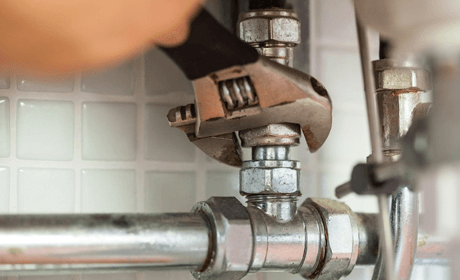 a pipe being tightened using a spanner, plumbing work