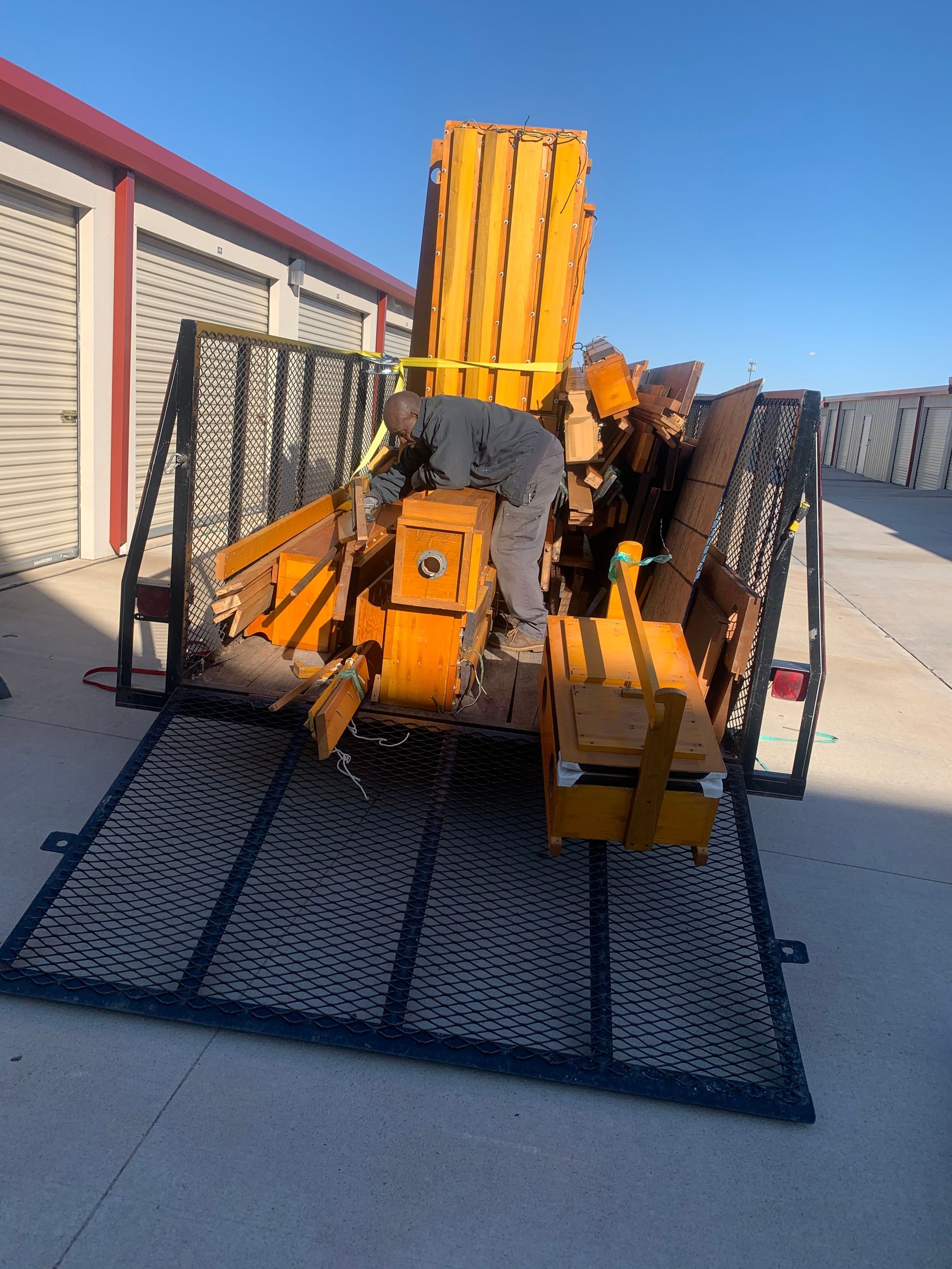Two movers loading boxes into the back of a moving truck at a house.