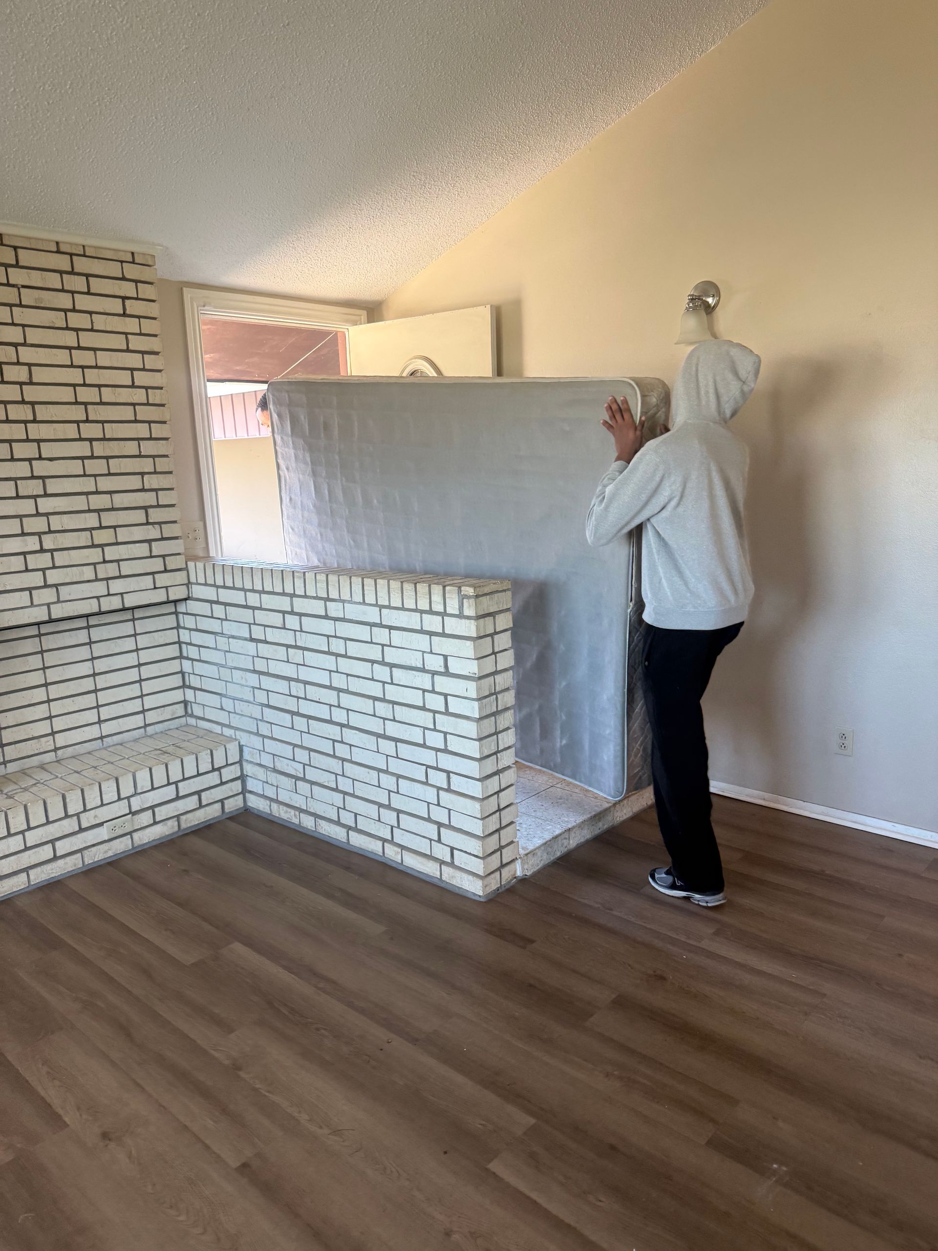 Two men loading a wrapped piano onto a truck from a dolly on a residential street.