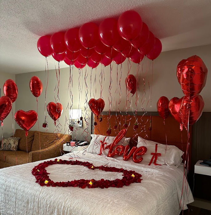 Red balloons and heart decorations in a hotel room, arranged for a romantic celebration.
