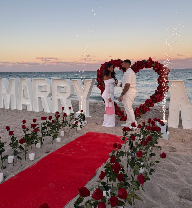 Couple at beach proposal. Red carpet, roses,