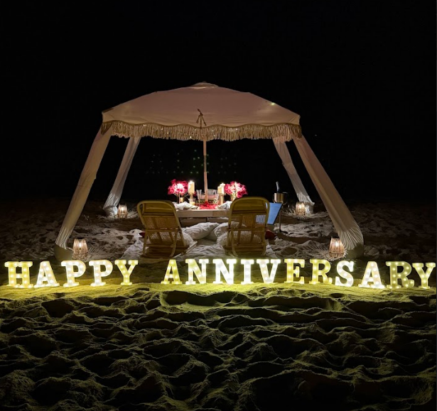 Romantic beach anniversary setup at night with lit