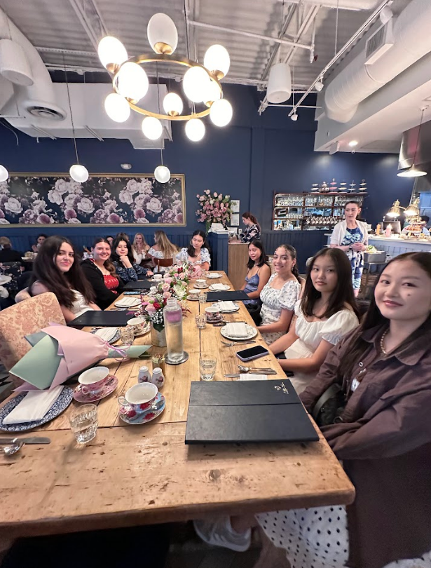 People at a table in a restaurant; blue wall, floral art, chandelier, server behind the bar.