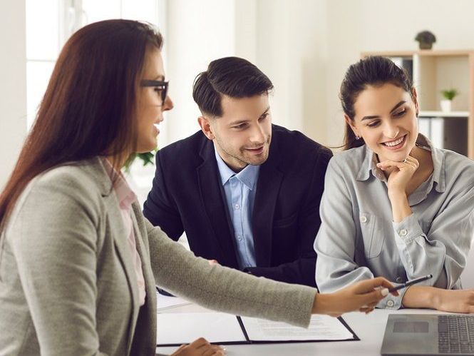 A man and two women are sitting at a table with a laptop.