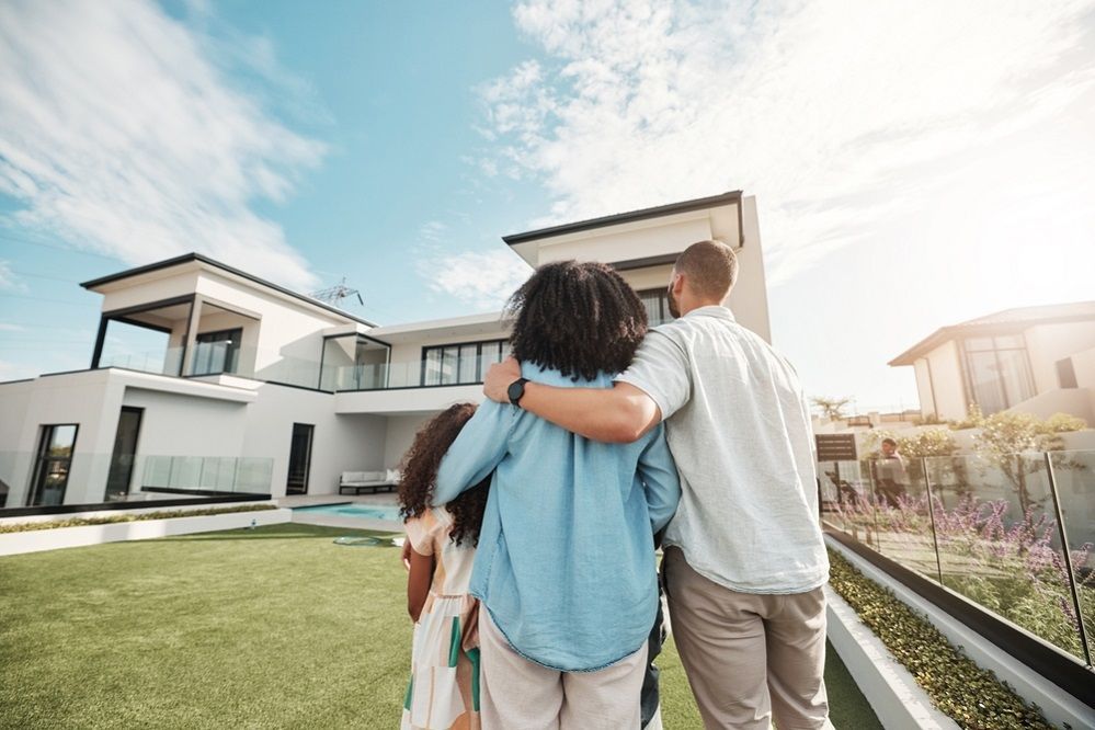 A family is standing in front of a large house.