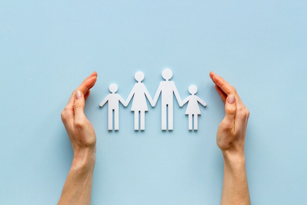 A person is holding a paper cut out of a family.