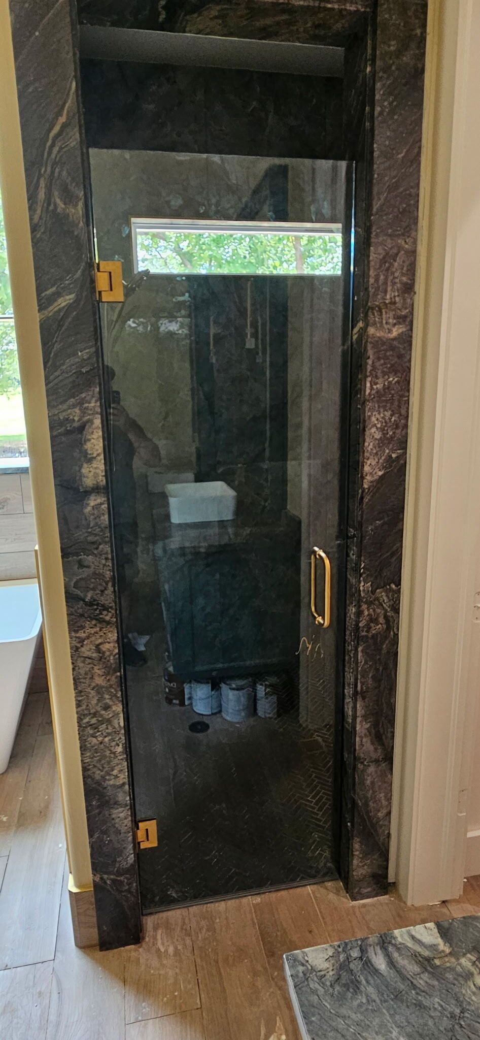 Glass door framed in dark wood, with a narrow window and a brass handle at the entrance.