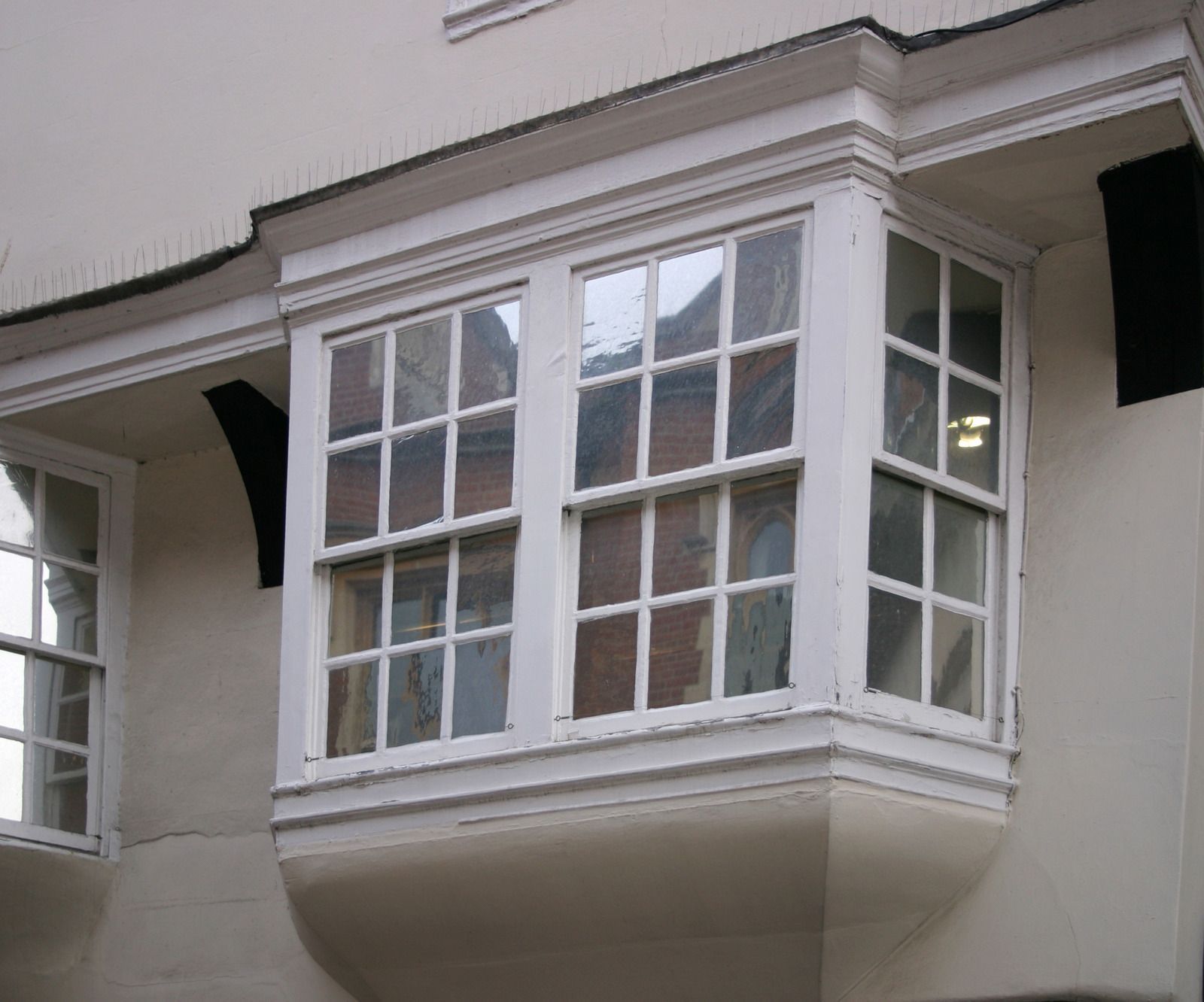 White bay window on a cream-colored building facade with multiple panes and dark trim