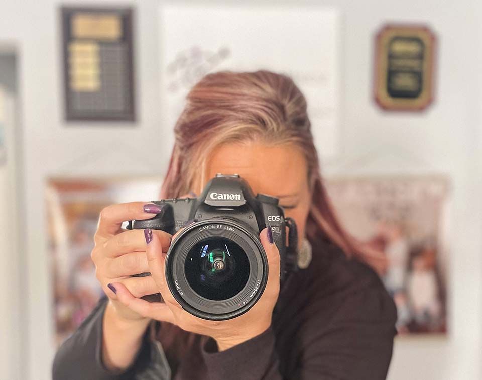 Person holding a Canon camera up to their face indoors