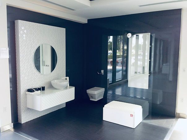 Bathroom showroom display with white and black decor, a floating vanity, and a large mirror.