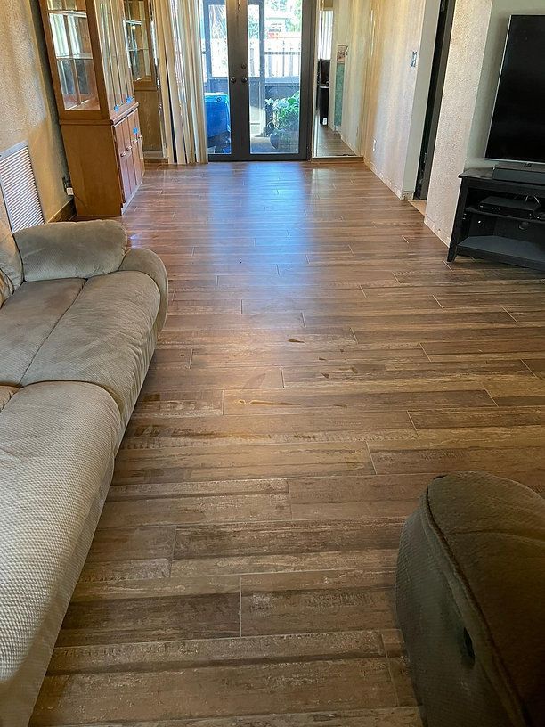A living room with wood-look flooring, a beige sofa, and glass doors to a patio.