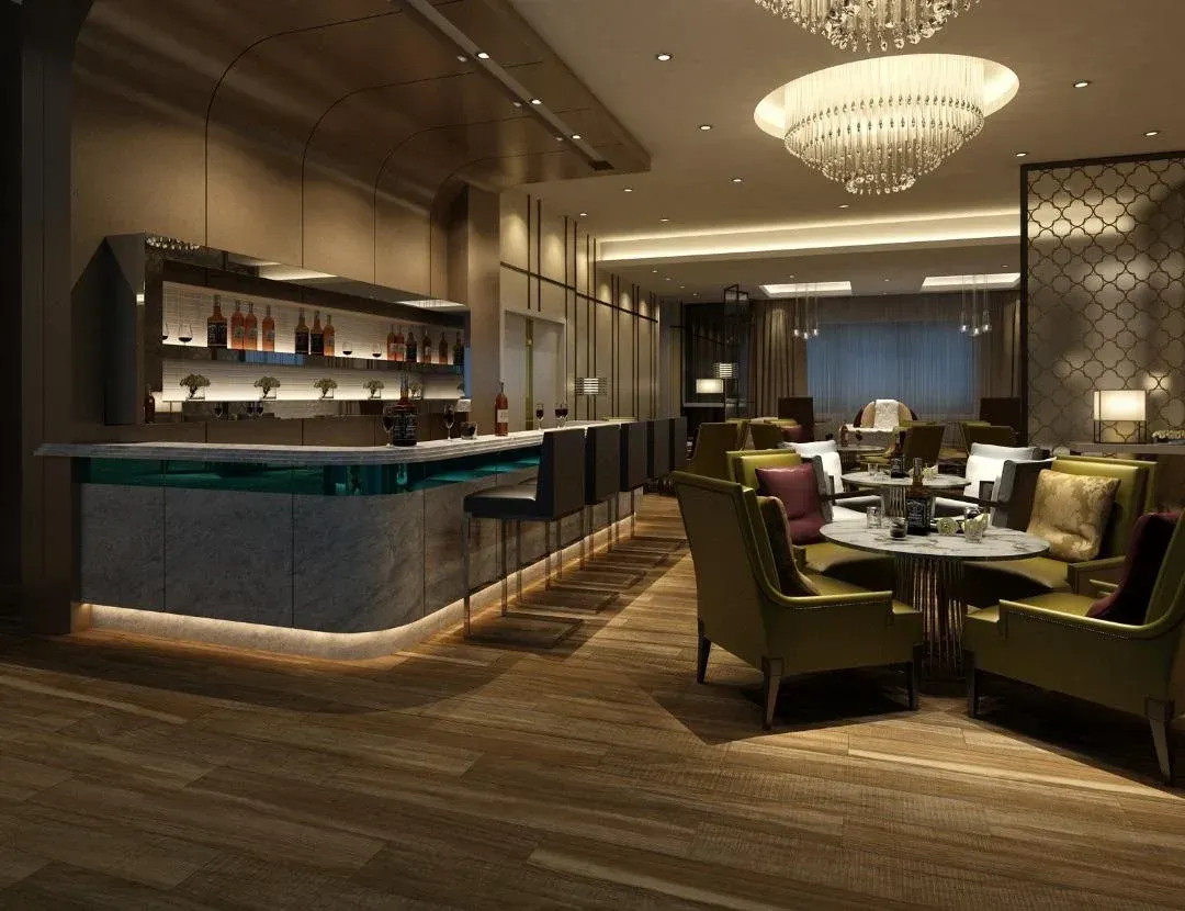 Upscale bar and lounge area with illuminated bar, seating, and chandeliers.