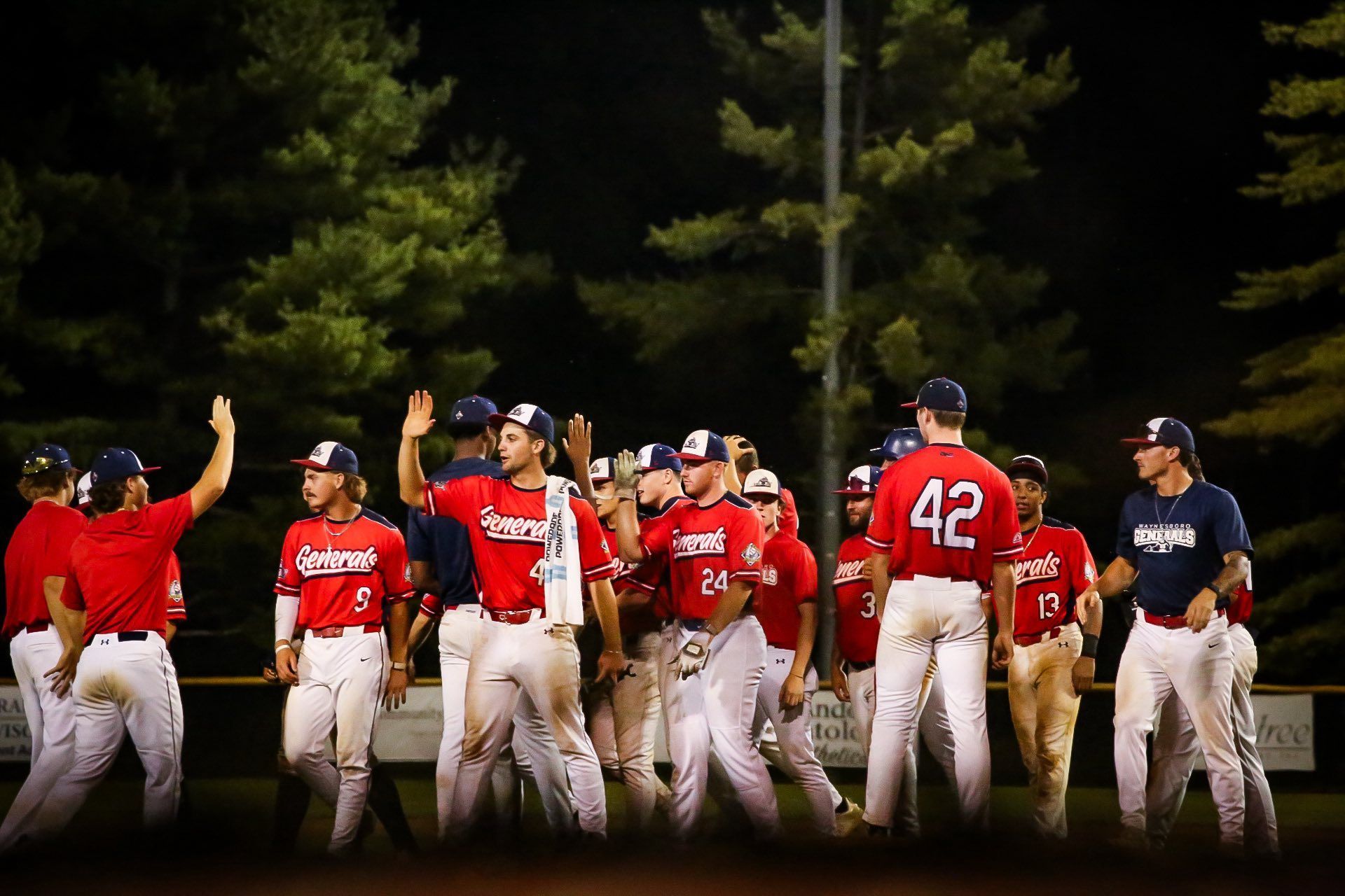 A baseball player is swinging a bat at a pitch while a catcher watches.