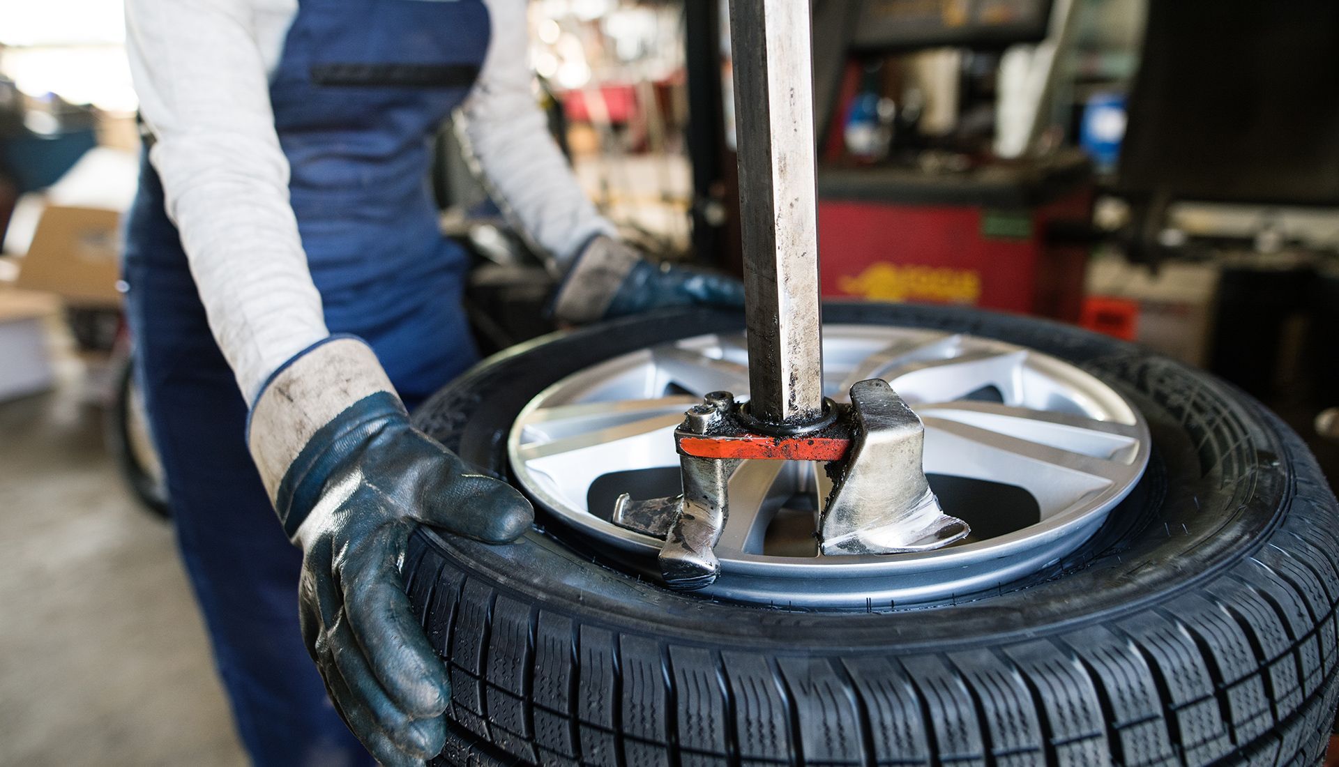 Mechanic using tire machine to remove a tire from a wheel in a garage.