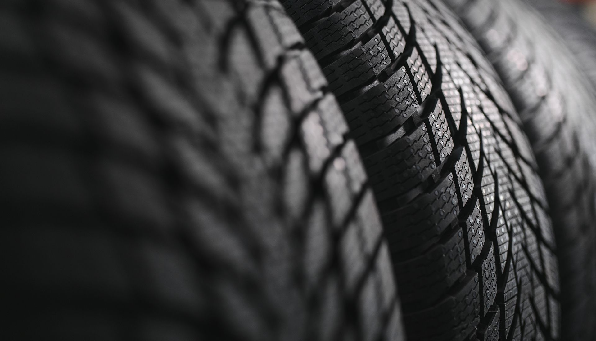 Close-up of stacked black tires with textured tread patterns.