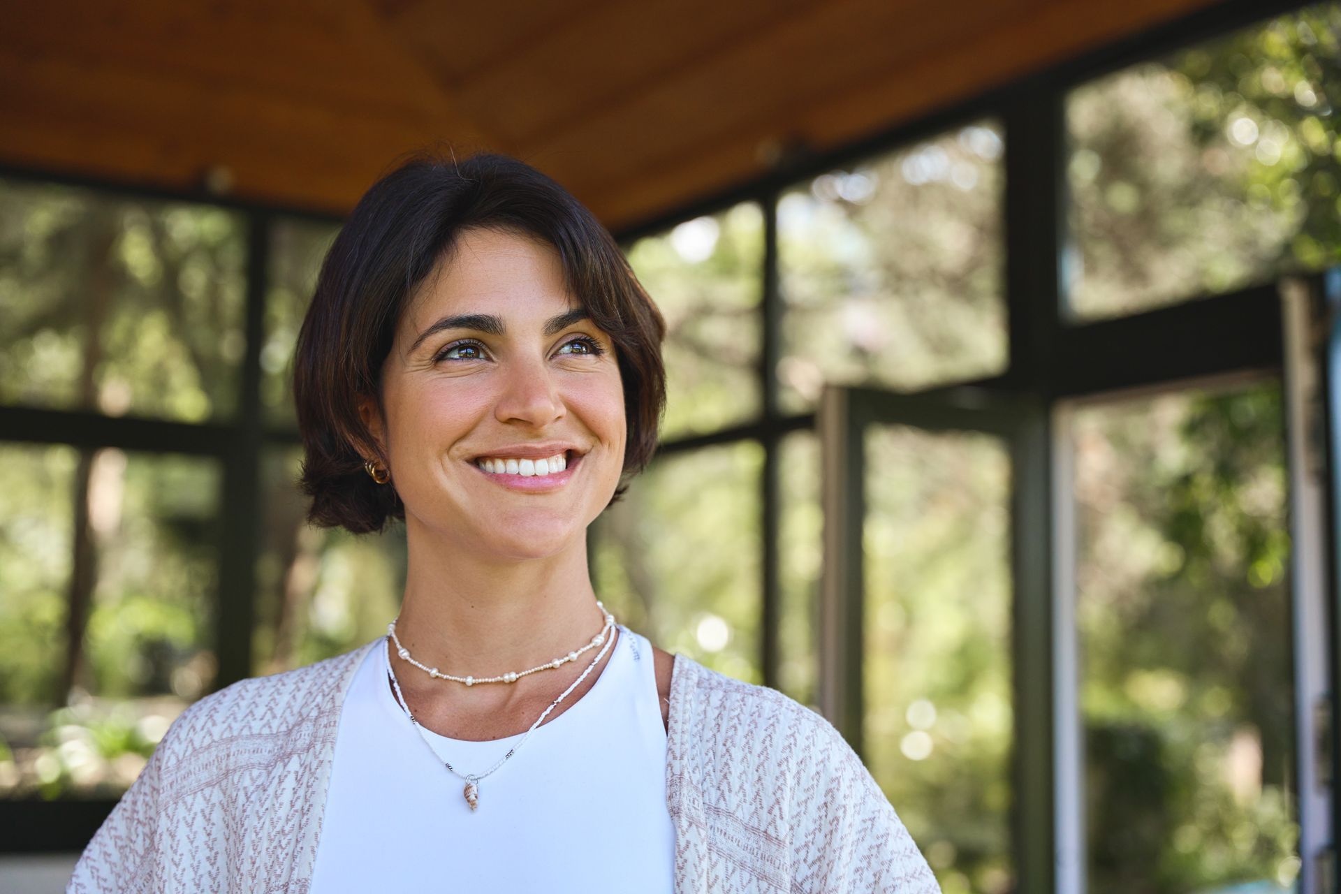 A woman is smiling while standing in front of a window.