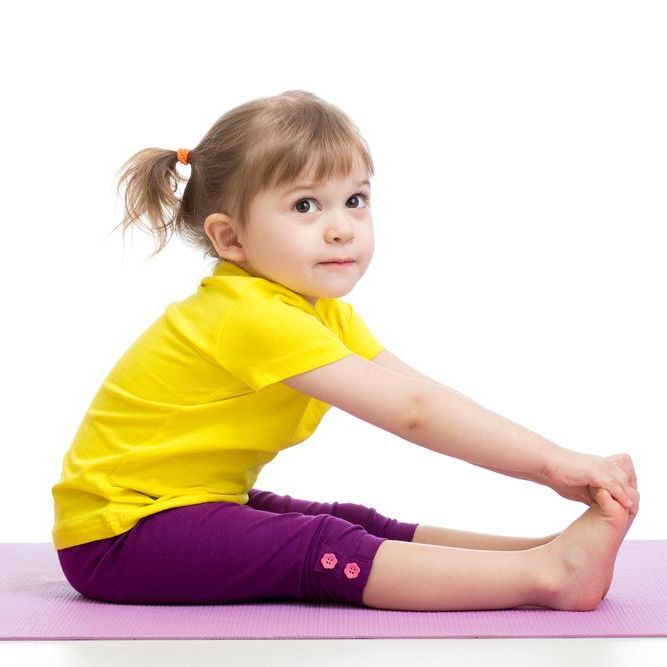 Girl in yellow shirt and purple pants stretching on a pink mat, touching her toes.