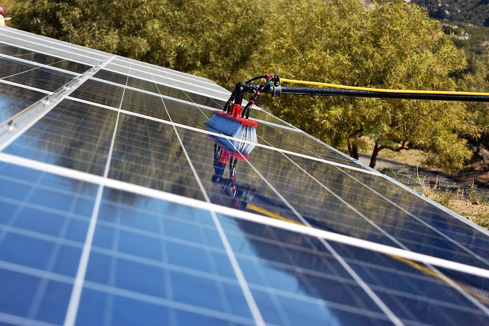 A person is cleaning a solar panel with a brush.