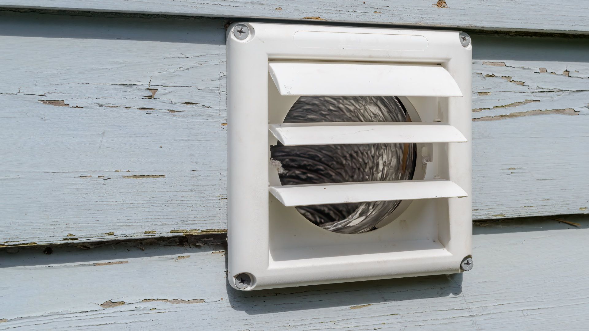A white vent on the side of a house.